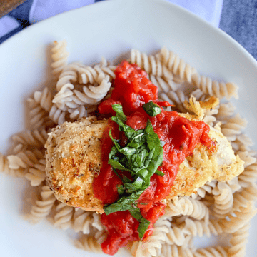 parmesan-less chicken served over noodles with marinara sauce and basil on top