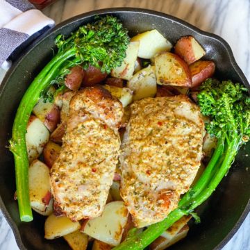 Pork chops in a cast iron pan with potatoes and broccolini
