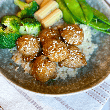 Orange Chicken Meatballs with broccoli, baby corn, snap peas and rice in a bowl