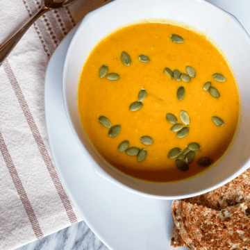 Pumpkin Curry Soup in a bowl with bread on the side