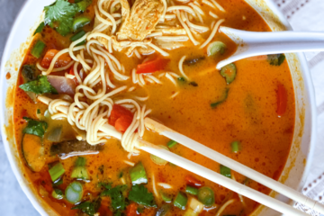 Gluten free Ramen noodles in spicy curry broth with chop sticks and big soup spoon.