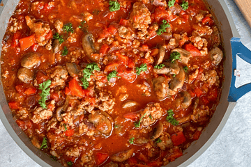 Veggie packed pasta sauce in a pan with mushrooms, red bell peppers and onions. Spatula on the side.