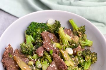 Paleo Beef and Broccoli in a a bowl with sesame seeds and green onion as garnish