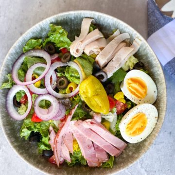 Chef salad with hard boiled egg, pepper, onion, and deli meat in a bowl