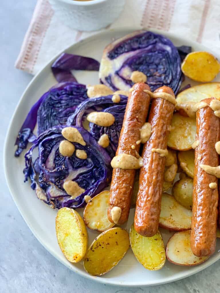 Sausages over roasted purple cabbage and potatoes with honey mustard sauce drizzled over